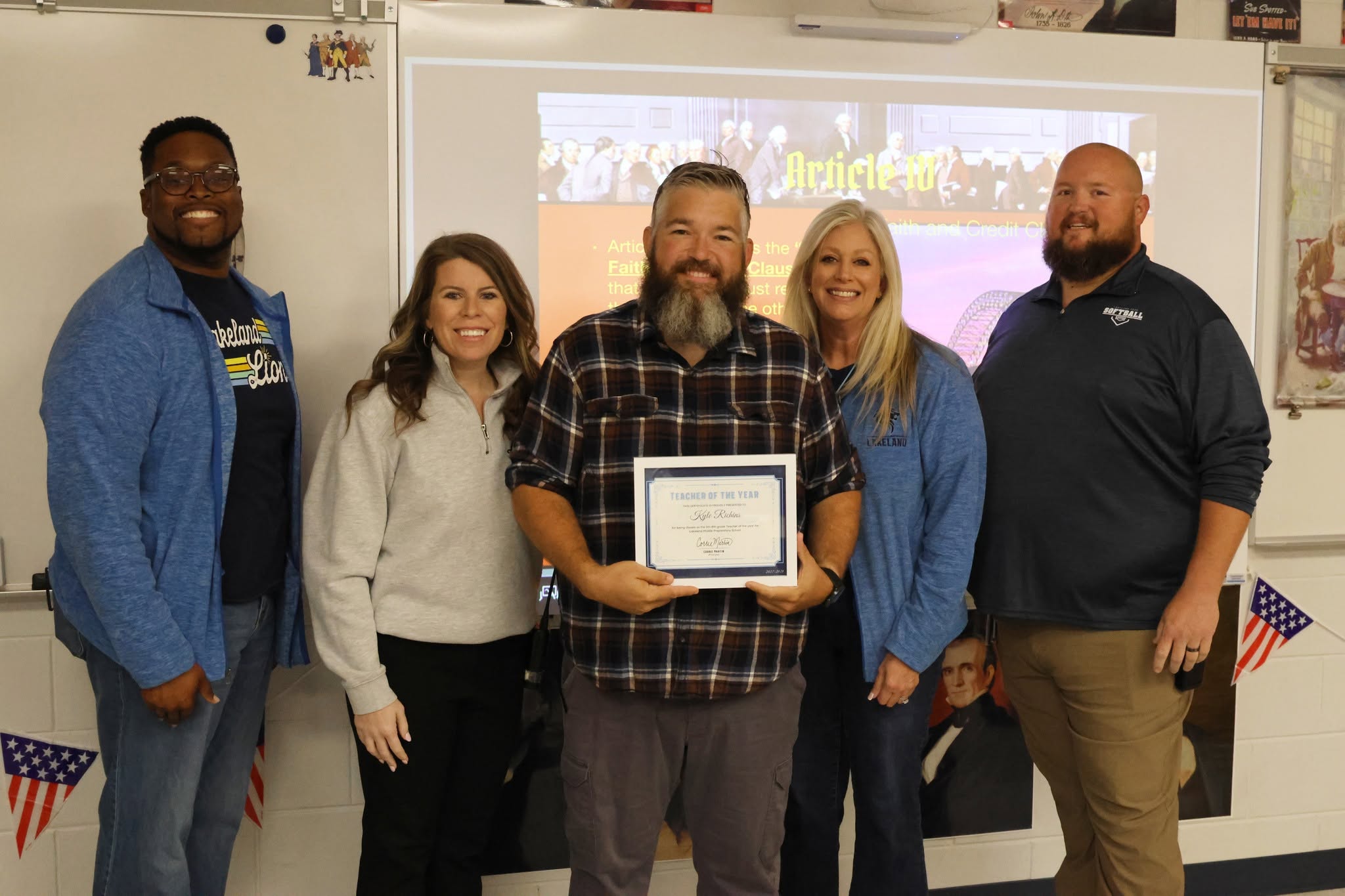 Kyle Richins, center, holds his Teacher of the Year certificate with four others in his classroom.